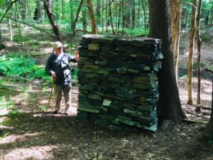 A person standing next to a tree in the woods.