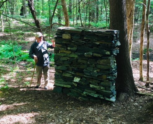 A person standing next to a tree in the woods.