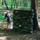 A person standing next to a tree in the woods.