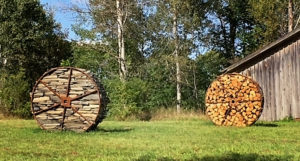 Two large wooden wheels in a field with trees