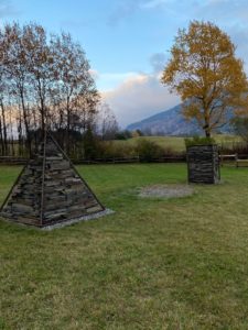 A grassy area with trees and a teepee.