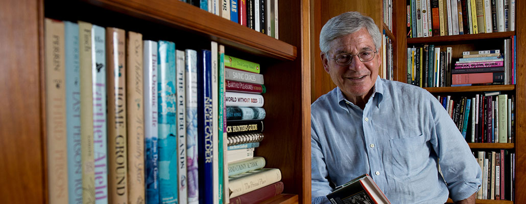 A man sitting in front of some books on a bookshelf.