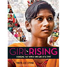 A woman standing in front of a wall with the word girl rising on it.