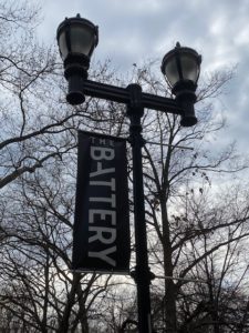 A street light with a sign hanging from it's side.