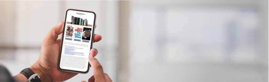 A person holding up their cell phone in front of a window.