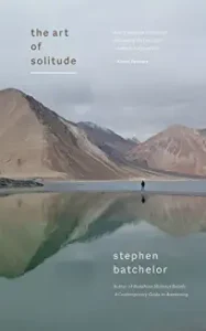 A person standing in the water near some mountains.