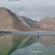 A person standing in the water near some mountains.