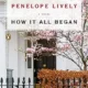 A white house with pink flowers and trees in front of it.