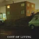 A van parked in front of a building with the words " cost of living ".