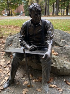 A statue of a man sitting on top of a rock.